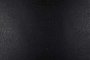 Closeup of black, rough background lit with dim light.