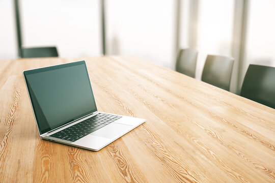 Modern Laptop On Wooden Table In Sunny Meeting Room With Large Window. 3D Rendering