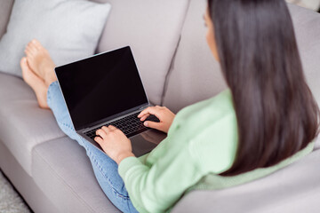 Back rear spine view photo of focused korean girl sit lie divan work remote laptop texting boss...