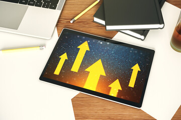 Top view of modern digital tablet monitor with creative abstract upward arrows hologram. Ambition and challenge concept. 3D Rendering