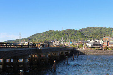 Fototapeta na wymiar View of Uji city with the Uji Bridge, Uji River, houses, mountain and blue sky, Japan