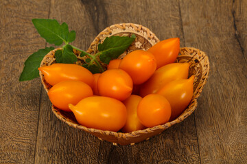 Yellow tomato heap in the wooden bowl