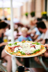 Kellner trägt Pizza im Restaurant Biergarten 