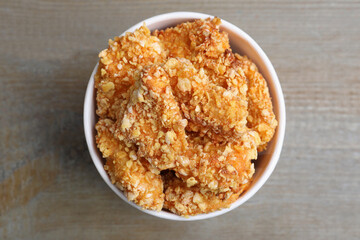 Bucket with yummy nuggets on wooden table, top view