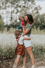 Happy family is playing, having fun on the field with flowers at sunset. Family and love concept....