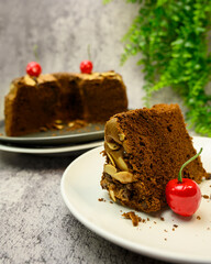 Chocolate Chiffon cake with almond and cherry fruit on white plate isolated on gray