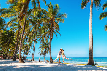 Kissing couple on tropical beach with palm trees - obrazy, fototapety, plakaty