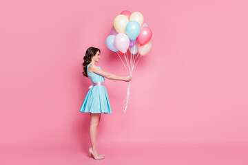 Full length body size profile side view of nice attractive charming smart feminine exquisite cheerful wavy-haired girl holding in hand delivering bunch balls isolated over pink pastel color background