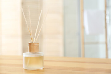 Reed air freshener on wooden table indoors. Space for text