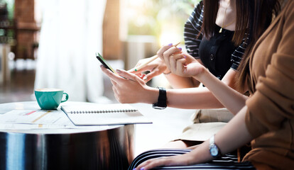 Two young asian woman working together and using technology from smart phone search information from internet