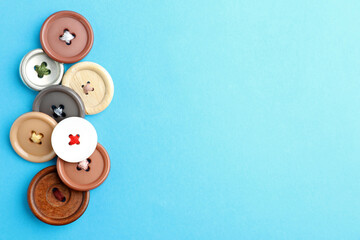 Many colorful sewing buttons on light blue background, flat lay. Space for text