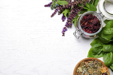 Flat lay composition with different healing herbs on white wooden table, space for text
