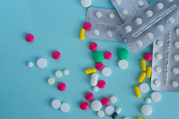 Multi-colored tablets of different shapes and colors. Placer pills and a stack of blisters. Medical concept, treatment of diseases and viruses, pharmacy, healthcare, vitamins.