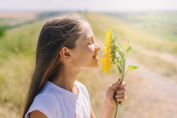 Portrait of a child girl sniffing a sunflower flower