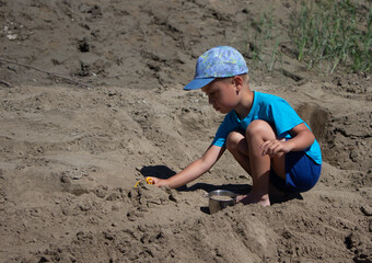 
boy playing in the sand by the river