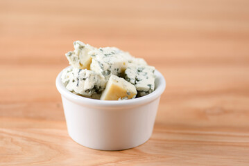 Cut cheese in a small white bowl. Snack, appetizer. Pizza ingredient.