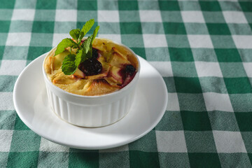 Delicious apple pie dessert served in a small white bowl over wooden table with green plaid tablecloth.