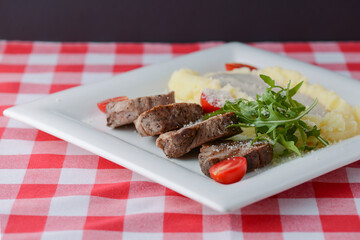 Mashed potatoes with gravy, meat, fresh greenery and raw organic vegetables.