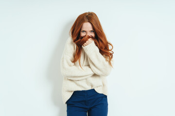 Bashful young woman hiding behind her hand