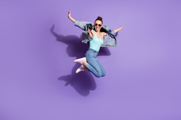 Fototapeta na wymiar Full length photo of playful carefree youth girl jump enjoy weekend wear good look outfit sneakers isolated over violet color background