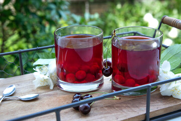 Fresh cherry juice on a wooden tray outdoor. Cherry compote
