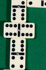 Close up of domino pieces with black dots in green table