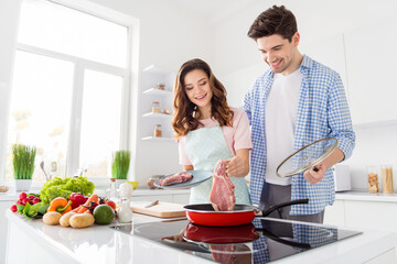 Portrait of two nice attractive cheerful friendly people cooking domestic fresh homemade meal in...