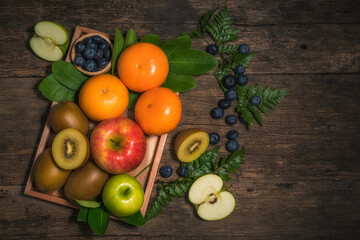 Fresh high vitamin c fruits, different fruits on old wooden table,The fresh apple, orange, blueberry, kiwi, Different raw fruits background. Healthy eating.