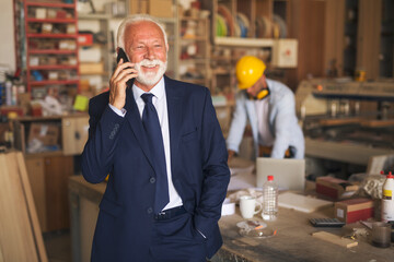 Senior man talking on the phone in a carpentry shop