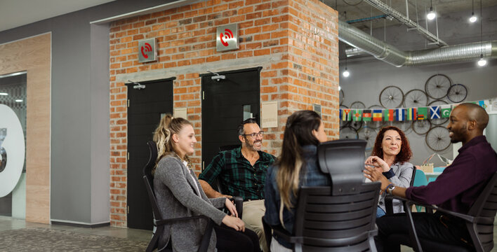 Diverse businesspeople smiling and talking together in a coworking workspace