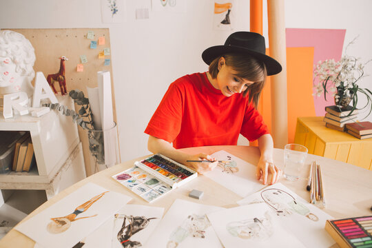Young smiling girl illustrator painter draw a storyboard for a movie or cartoon in workshop
