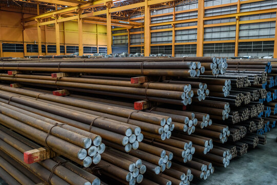 Pack of steel round bar stack in layer inside large distribution warehouse. Steel warehouse logistics operations.