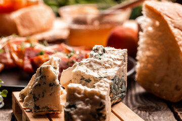 A piece of blue cheese on a wooden board with ciabatta and fresh juicy peach. Food recipe background. Close up