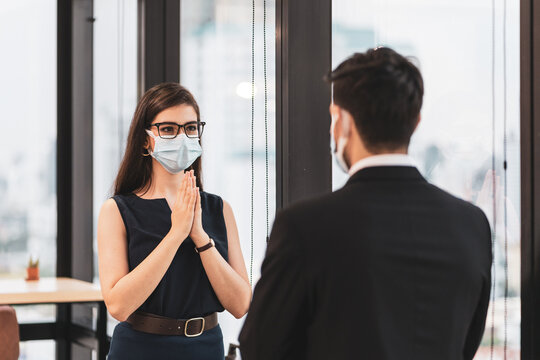 woman wear face mask greeting in new normal way (pray) in office