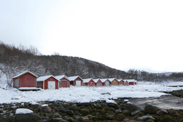 the photo shows Scandinavian wooden buildings with a forest in the background. snow around and big drifts