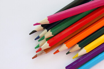 Fototapeta premium Colored pencils white background. Lots of different colored pencils. Colored pencil. Pencils are sharp. Pencils lie on the left. Close-up. Copy space. Background. Flat lay.