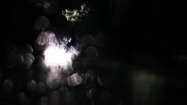 Abstract moving light spots form a fantasy image. Reflections of headlights on the windshield in water droplets. Cars drive in the rain. 4K.