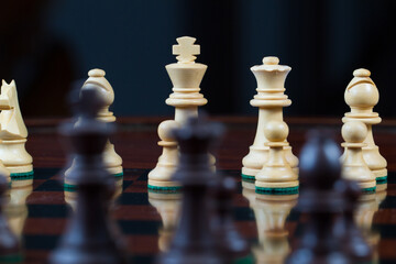 Closeup battle white versus black. Set of chess figures on wooden playing board