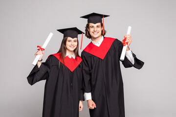 Young couple posing with their diplomas on white background