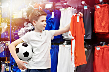 Boy with ball and red t-shirt in football store