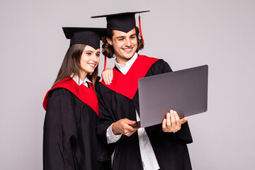 Young graduation couple holding laptop on white background