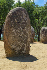 Neolithic site in southern Portugal. A megalith sits off-center with rows of other standing stones in background. Ancient look and texture with copy space.