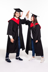 Two happy college graduates giving high five smiling after receiving diplomas over white background.