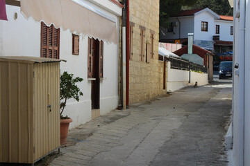 A narrow street of a Cypriot village with white houses and brown wooden shutters. Cyprus.