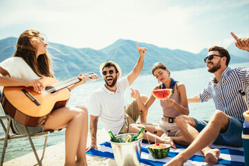 Group of friends with guitar having fun on the beach.