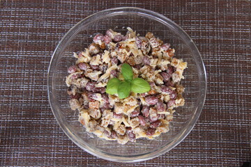Salad with canned beans and crackers, decorated with Basil, in a glass Cup on a brown napkin, top view