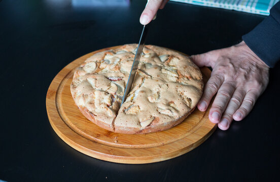 Men's Hands Cut A Homemade Apple Pie Lying On A Round Wooden Board.