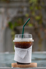 Iced Americano coffee in take home plasttic cup on glass table