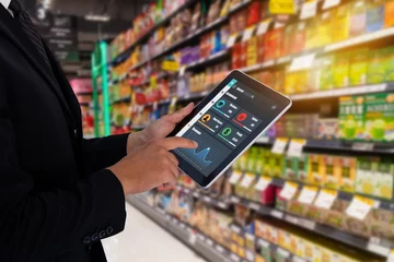 Fotobehang iot smart retail in the futuristic concept, the retailer hold the tablet and use augmented reality technology monitor data of out of shelve, price, planogram, campaign of compliance in the real time © Monopoly919