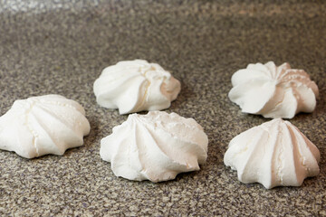 Off white marshmallow roses on a spotty surface. Delicious homemade meringue cakes. The concept of home cooking of food.